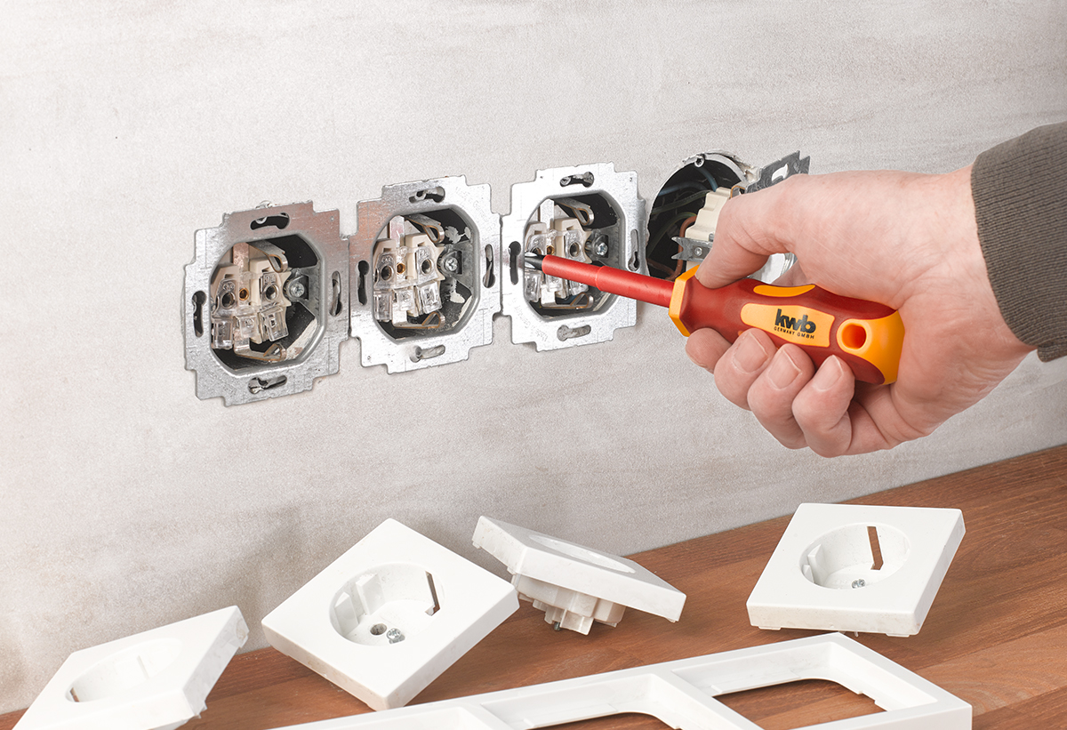 Στη φωτογραφία απεικονίζεται ένα χέρι με το κατσαβίδι που φτιάχνει πρίζες